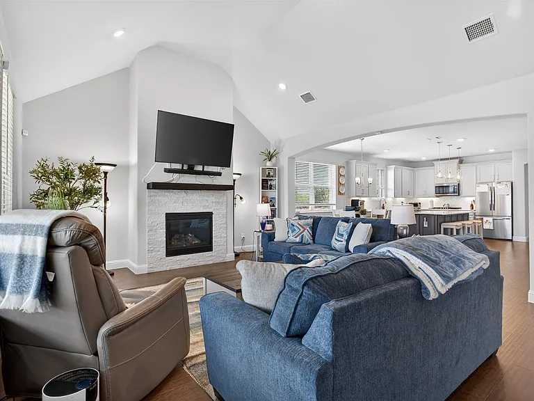 Spacious living area featuring a vaulted ceiling, recessed lighting, and wood-finish flooring