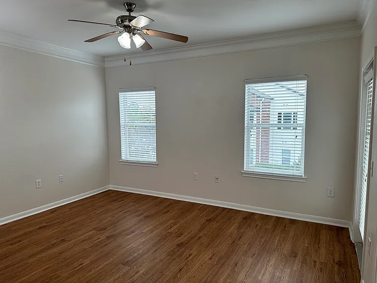 Bright and spacious room with elegant wood-style flooring, large windows and ceiling fan, perfect for cozy living. Bright and spacious room with elegant wood-style flooring, large windows and ceiling fan, perfect for cozy living.