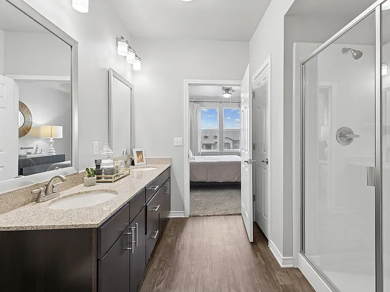 Bath with dark cabinetry, beige speckled granite countertops, and hard surface flooring