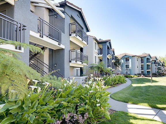 Exterior of apartment community with grass area and flowers.