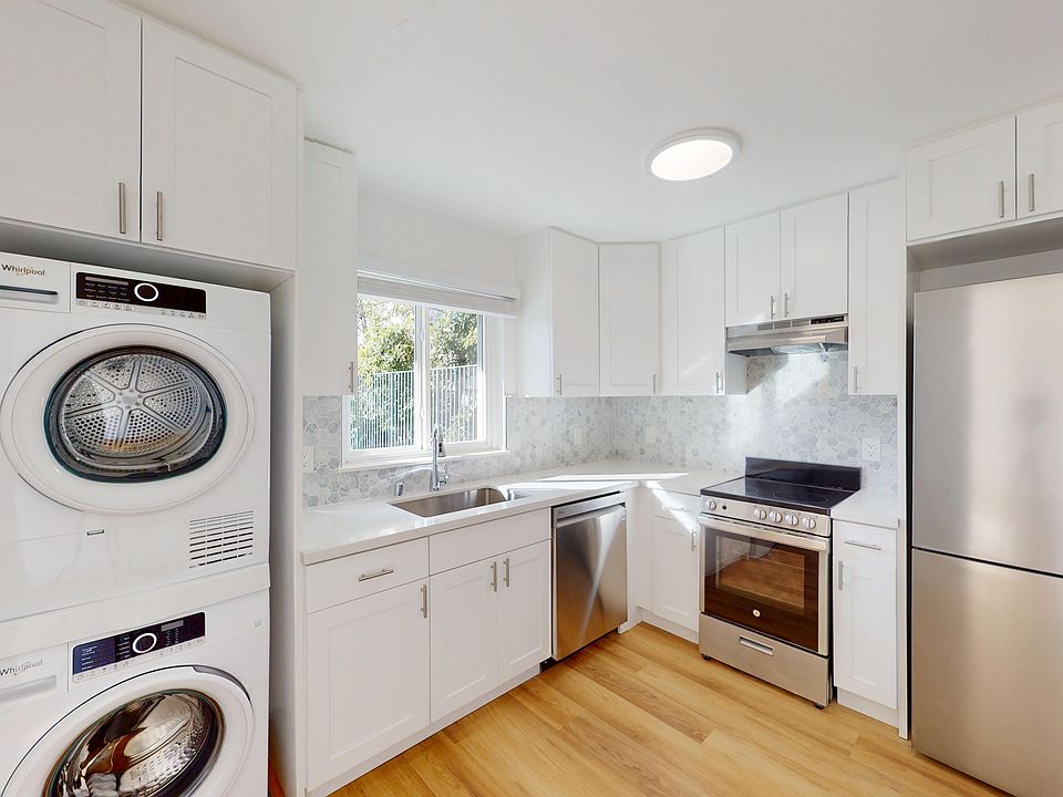 Kitchen with cabinets, stacked washer-dryer, stainless appliances, wood floor