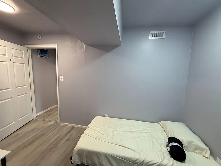 Private bedroom with durable plank flooring, neutral paint, and space for a bed plus essentials, near the hallway.