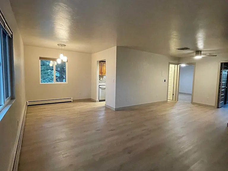 View from far corner of living room area looking at kitchen, bath and bedroom doors