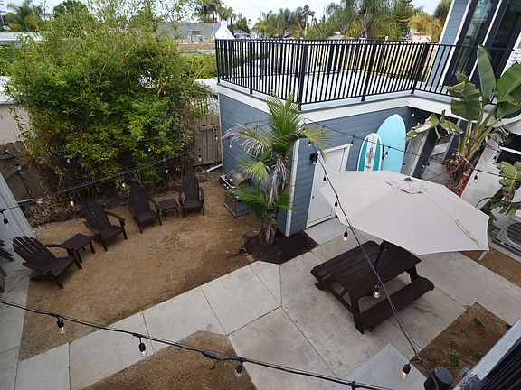 common area patio with community bbq, solo stove fire pit, and Adirondack chairs and picnic table with market umbrella