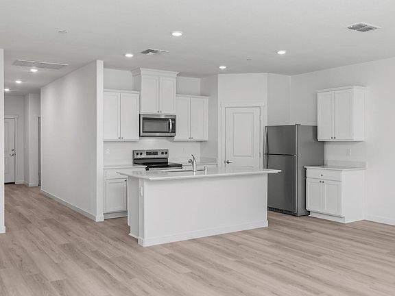 The kitchen has stainless steel appliances and plank flooring.