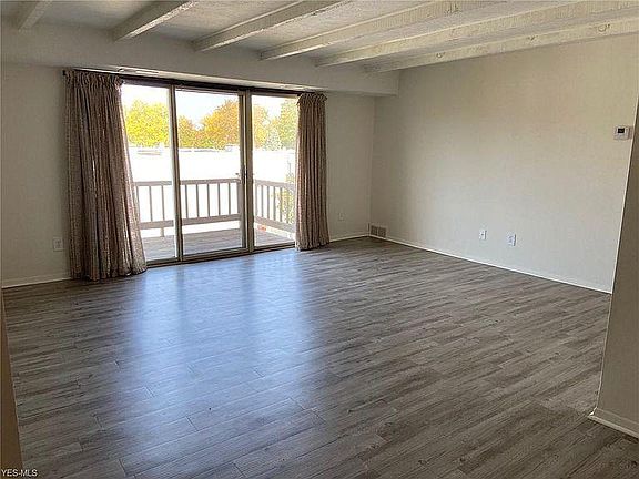 Living room with a large balcony that overlooks a peaceful grassy area.