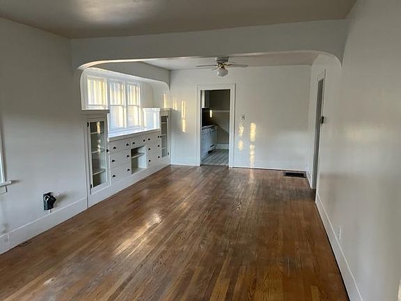 Living and dining areas with built-in drawers and glass cabinets. Wood floors.
