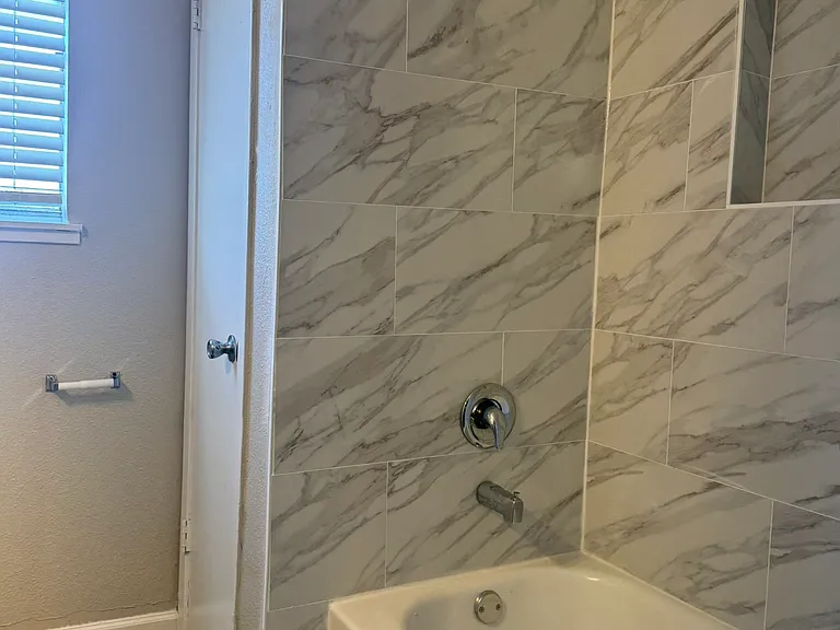 This modern bathroom features a beautifully tiled tub surround with a built_in niche, complemented by clean finishes and warm natural light.