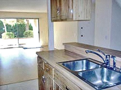 kitchen looks out thru living to patio and green courtyard
