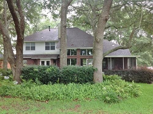 Back of home, view from golf course showing live oaks and pr