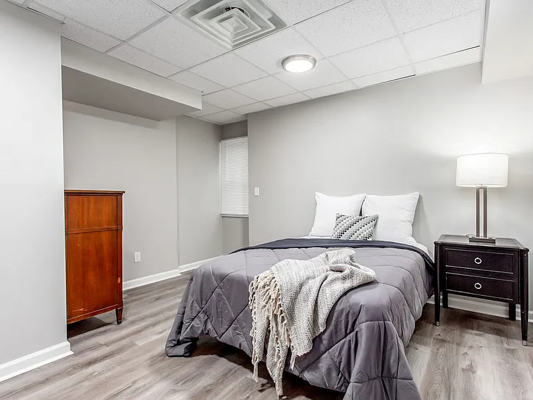 Large bedroom with dresser, nightstand and lamp.