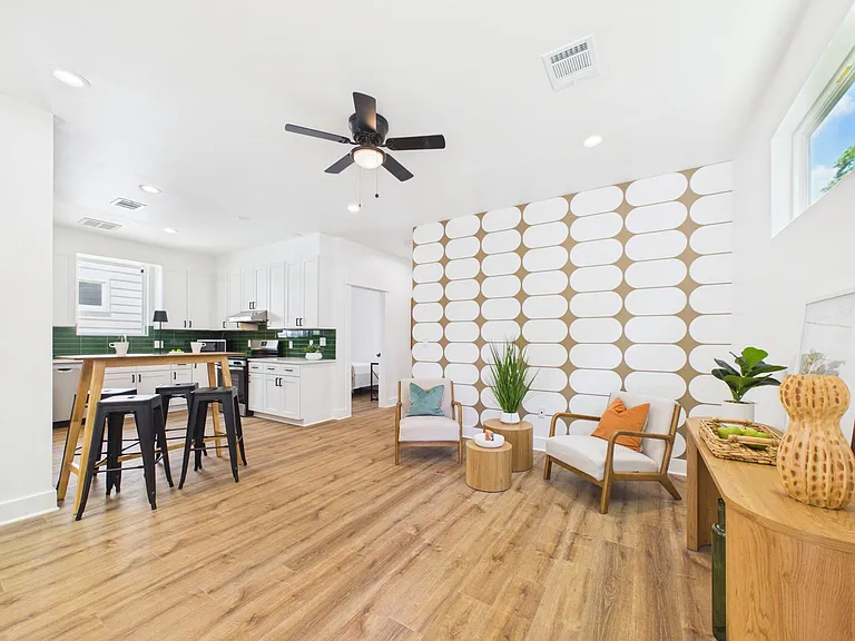 Open-concept living area with adjacent kitchen, bar seating, and durable wood-look flooring for easy everyday use.