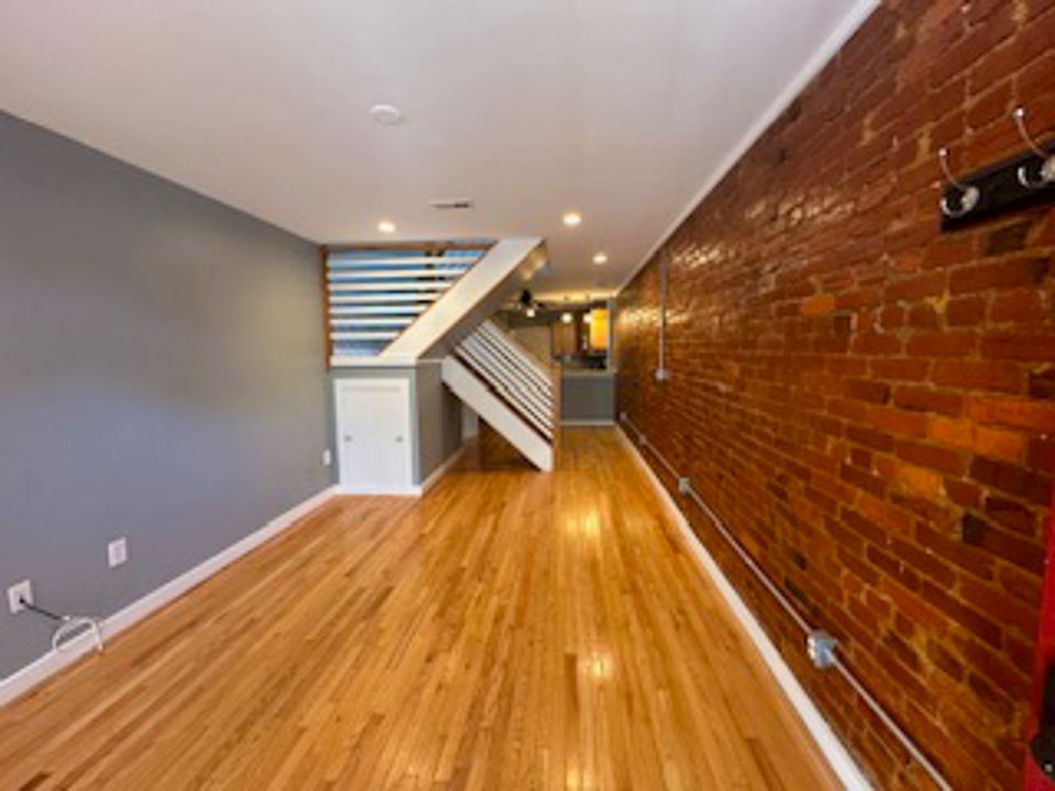 Open floor plan living room, with exposed brick wall