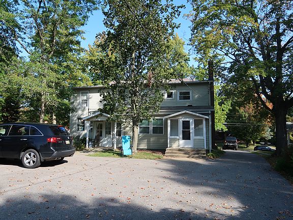 Rear of the house, parking pad visible. Available unit entry is on the left.
