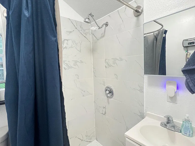 Updated bathroom with a tiled walk-in shower, curved curtain rod, and vanity with mirror for everyday storage.
