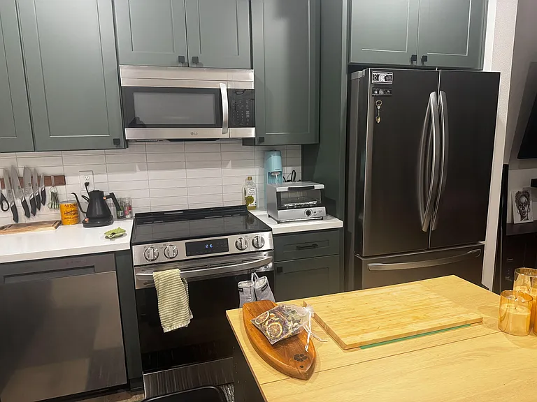 Well-equipped kitchen with stainless-steel refrigerator, range, microwave, ample cabinetry, and generous prep counter space.