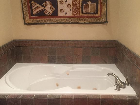 This large bathroom features tumbled stone and a separate walk-in shower, plus two pedestal sinks. There are two full bathrooms. One is off bedroom and one is off living room.