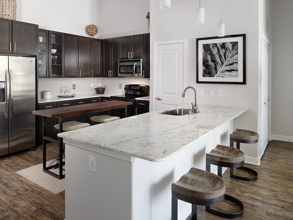 Kitchen with espresso cabinetry, granite countertops, tile backsplash, and stainless steel appliances