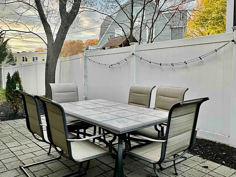 Outdoor dining area with string lights, manicured landscaping, and space to relax or entertain.