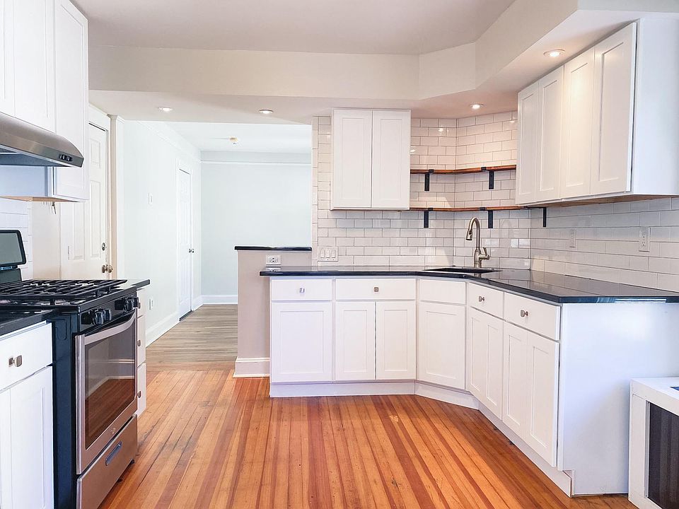 Modern renovated kitchen with black granite counters, white shaker cabinets and SS appliances.