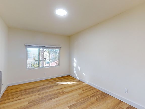 Spacious room with wood-like flooring and a large window offering natural light