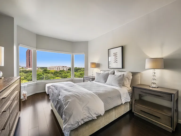 Secondary bedroom framed by a bay of windows and treetop views.