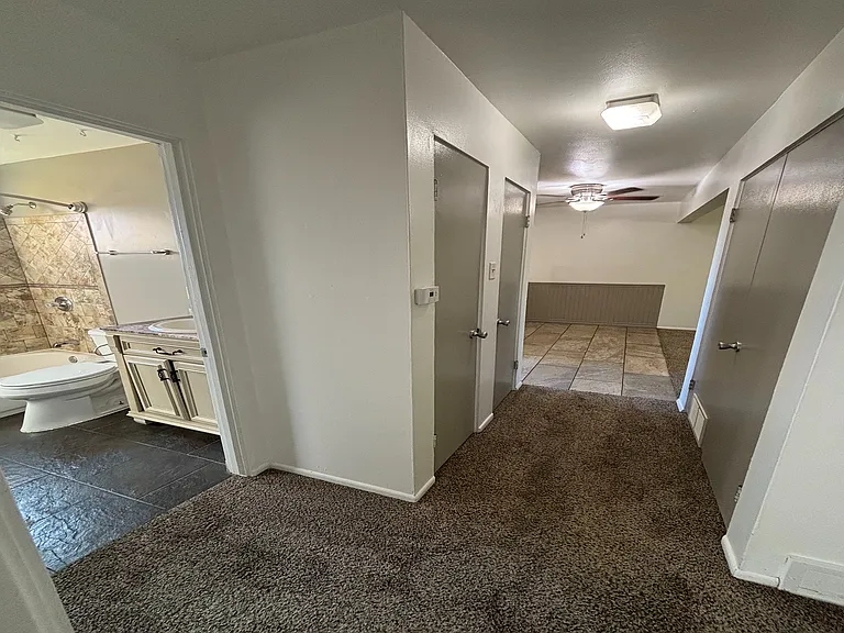 Inviting hallway with sleek hardwood floors and pristine white doors, leading to cozy living spaces.