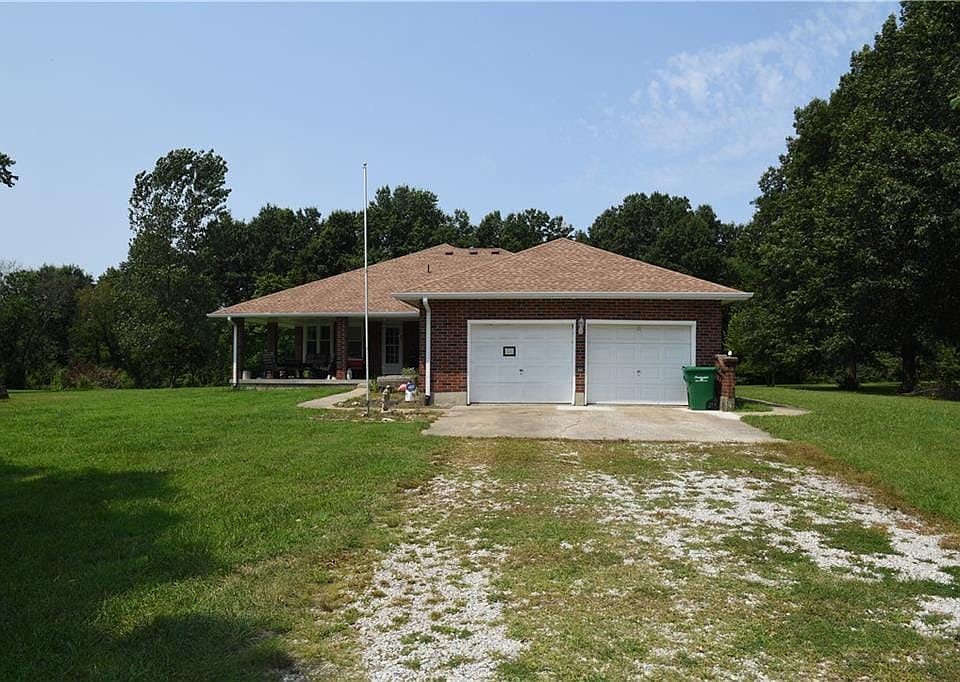 Brick exterior with a brown shingle roof, covered front porch, and an attached two-car garage
