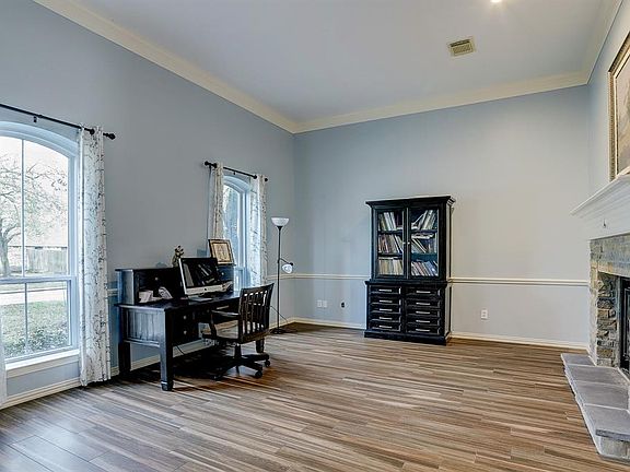 To the left of the entry is this large formal living room or study, featuring high ceilings, crown moulding, two front facing windows, and wood-look tile flooring. Stone surround was recently added, and fireplace is two sided with the adjoining forma