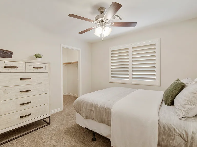 Bedroom 1 features a dresser, queen bed, nightstand and a walk-in closet