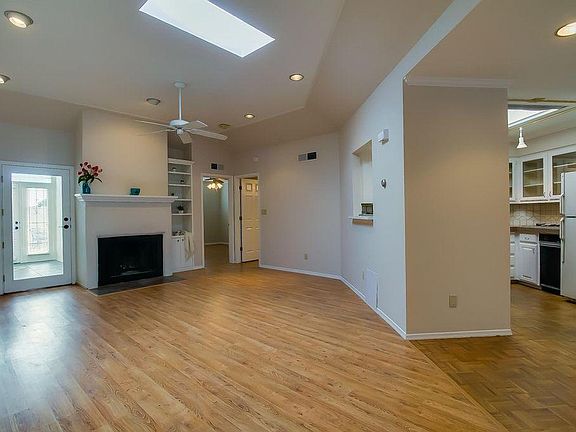 Cozy living room with vaulted ceilings, skylights, ceiling fan, fireplace and built-in bookshelves.