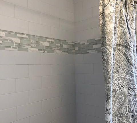 Tub/shower has beautiful white subway tile and glass/marble details.
