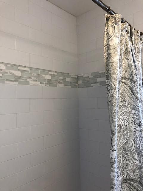 Tub/shower has beautiful white subway tile and glass/marble details.