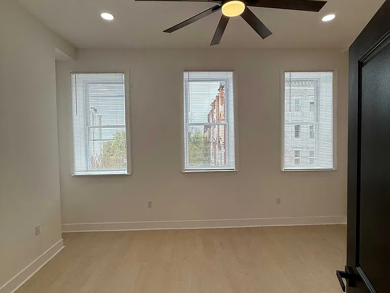 Bedroom with large modern ceiling fan and large windows.