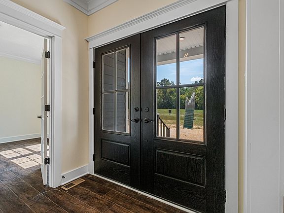 A set of black double front doors with glass panels in a residential entryway, adjacent to a sunlit