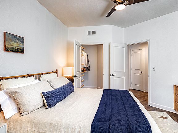 Spacious apartment bedroom with large closet and wood-style flooring.