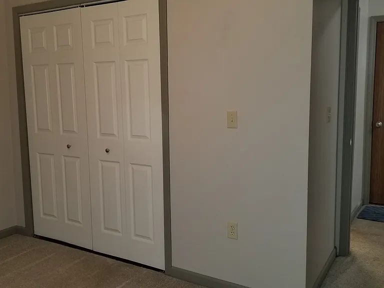 Main floor bedroom. Double doors are laundry closet area. Brown door in hallway leads to garage.