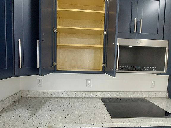 Cabinetry: Deep blue shaker-style cabinets with raised trim and sleek brushed nickel/silver hardware.