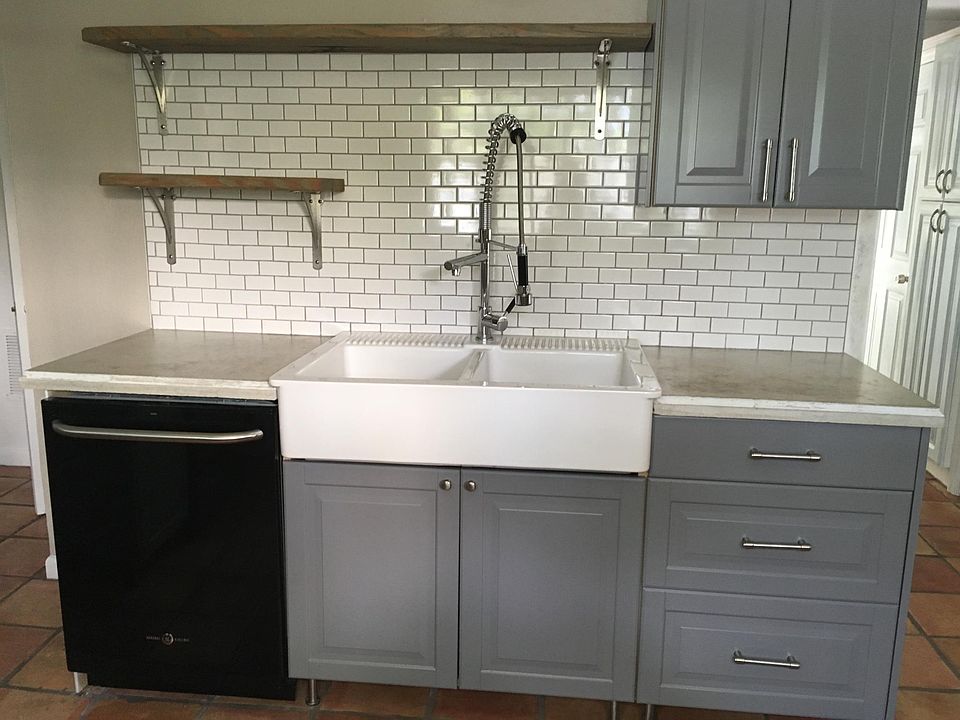 Farmhouse sink and subway tile backsplash with dishwasher in