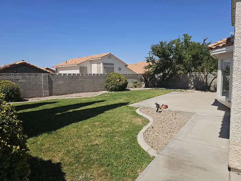 A verdant backyard offers a concrete patio and gravel accents, perfect for outdoor enjoyment.