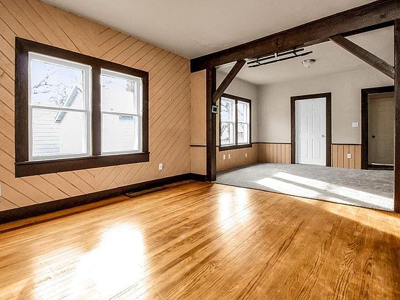 hardwood floors in living room. Carpet in additional living or dining room. White door on left is half bath with laundry hook ups. White door on right leads to flex room which could be a third bedroom or office. Kitchen is off to the right.