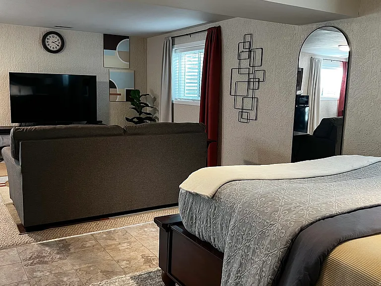 Comfortable queen bed with cozy lighting and nearby workspace for extended stays.