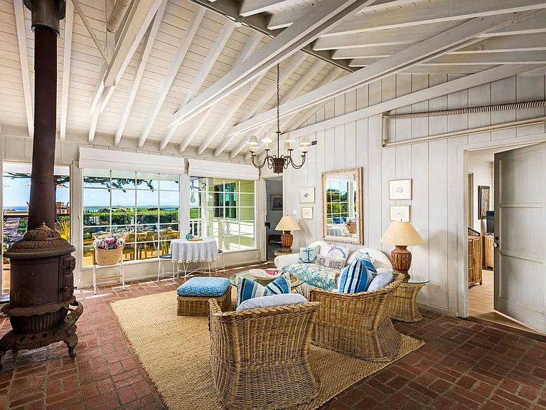 The lanai with original brick floors and cozy seating with ocean views. Original wood stove is decorative only.