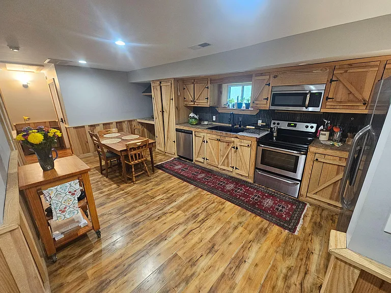 Eat-in kitchen with ample wood cabinetry, full stainless appliance suite, and a dedicated dining area beside the sink.