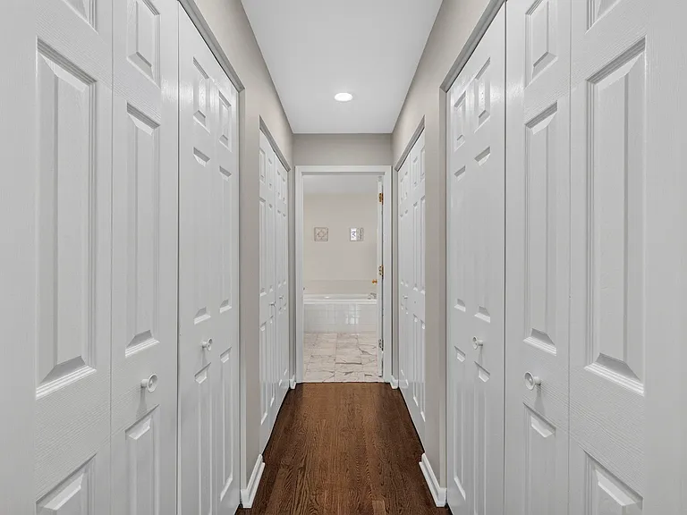 Beautiful Walk-through Closet Corridor with double-sided built in storage, leading to the primary bathroom.