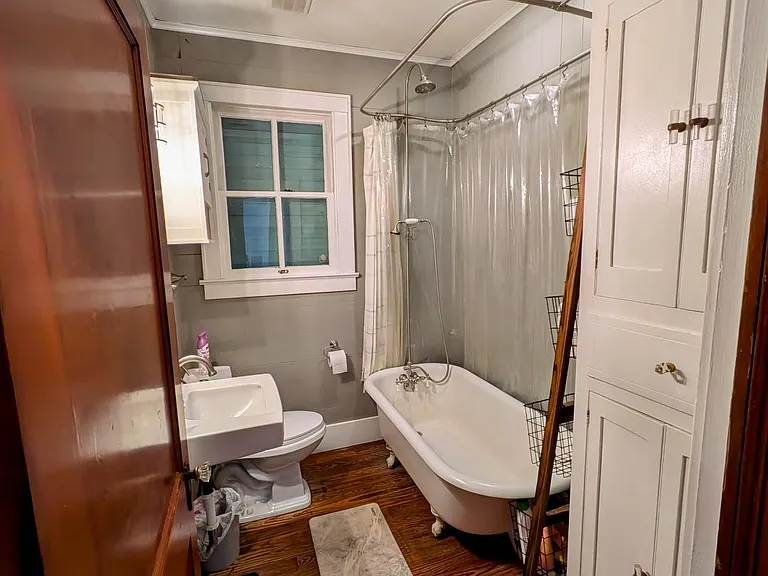 Full bathroom with vintage cast iron tub, fixtures and large storage cabinet.