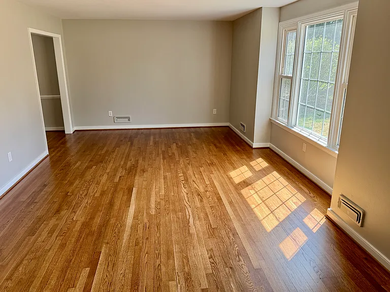 Spacious living room with refinished hardwood floors and a big picture window that floods the room with natural light.