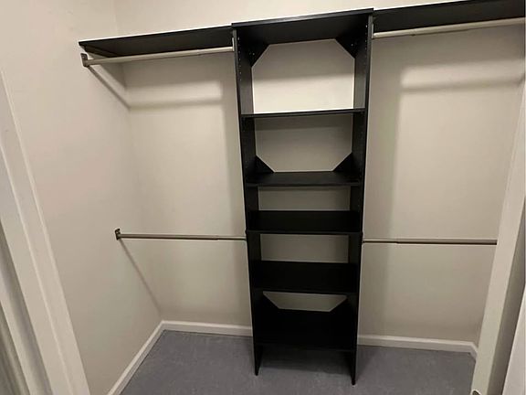 Primary walk-in closet featuring custom shelving and generous storage.