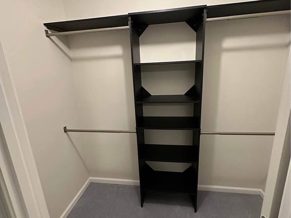 Primary walk-in closet featuring custom shelving and generous storage.