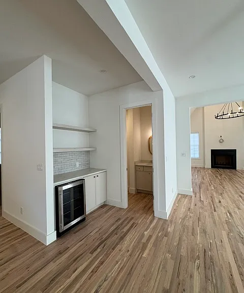 Dry bar with mini wine fridge with powder room off of the side of the open informal dining area